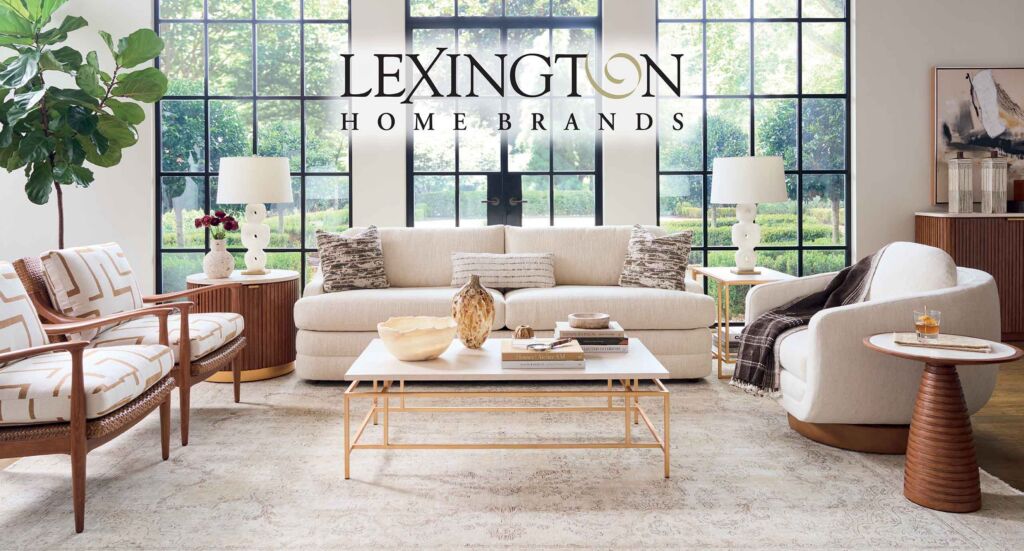 Lexington Fall Sale at IDS, August 27 - Sept. 30, 2026. Living room with a beige sofa, patterned chairs, glass coffee table, and large grid windows; Lexington Home Brands banner across the top.
